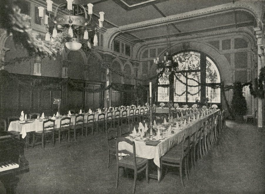 Historische Fotografie des kleinen Festsaals mit langen gedeckten Tafeln und einem Rundbogenfenster
