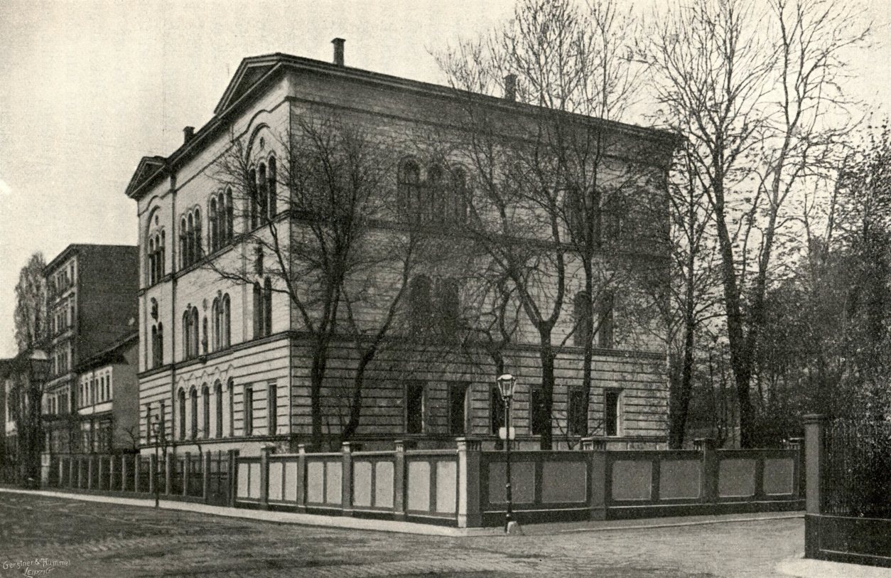 Historische Fotografie des Logenhauses der Logen Apollo und Balduin an einer Straßenecke, umgeben von kahlen Bäumen